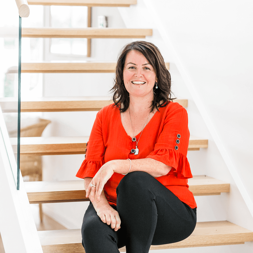 kelly walsham sitting on the stairs smiling at the camera